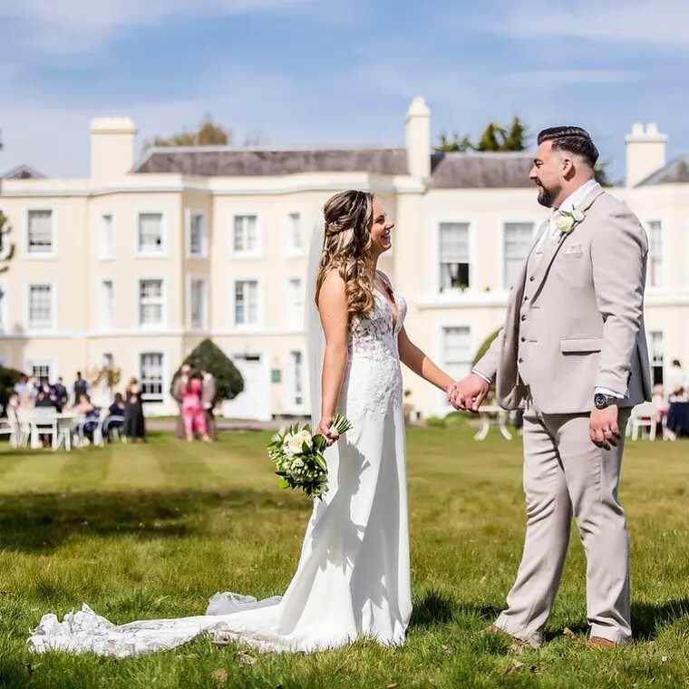 Couple standing in Burnham Beeches Hotel grounds, after their wedding ceremony
