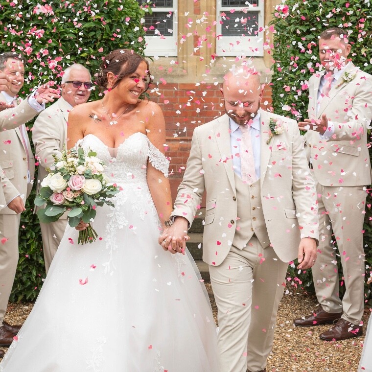 A bride and groom with wedding flowers and confetti 