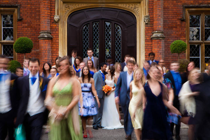 Bride and groom kissing whilst blurred people walk away