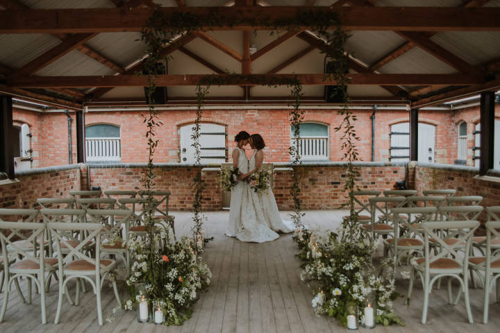 Two brides embracing at the front of a wedding ceremony set up 