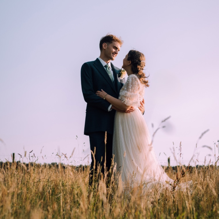 Couple embracing in a field at sunset.