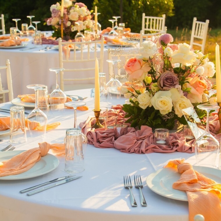 Circular wedding table decoration with orange napkins and spring coloured floral centre piece.