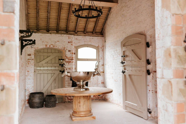 Large room with distressed brick, circular wooden table in the center with silver dish with stags heads on either side