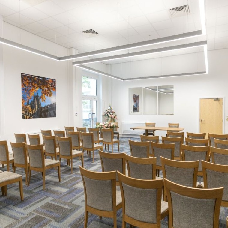 Ceremony room in Shire Hall, Gloucester. Grey and oak chairs. Three large mirror and a photos representing Gloucester. Large flower bouquets with greens, whites, and light pinks and purple. 