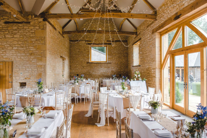 Inside the Threshing barn set for a wedding ceremony with round and long tables