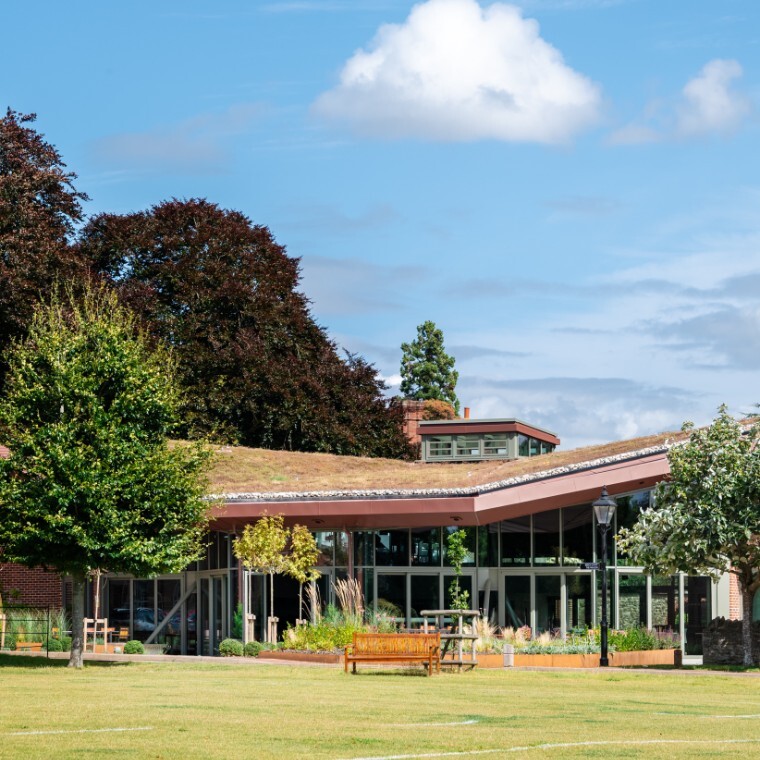 Large modern pavilion set in gardens with bench in front