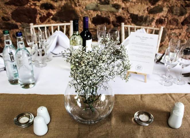 Vase of small white flowers in the middle of a table