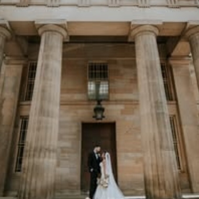 Bride and Groom standing in front of Old building with large pillars either side of them