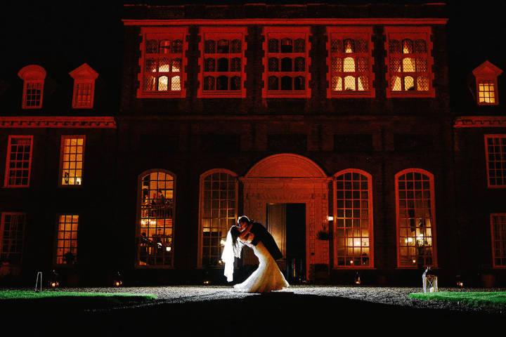 Bride and groom deep dip kiss outside Gosfield Hall wedding venue