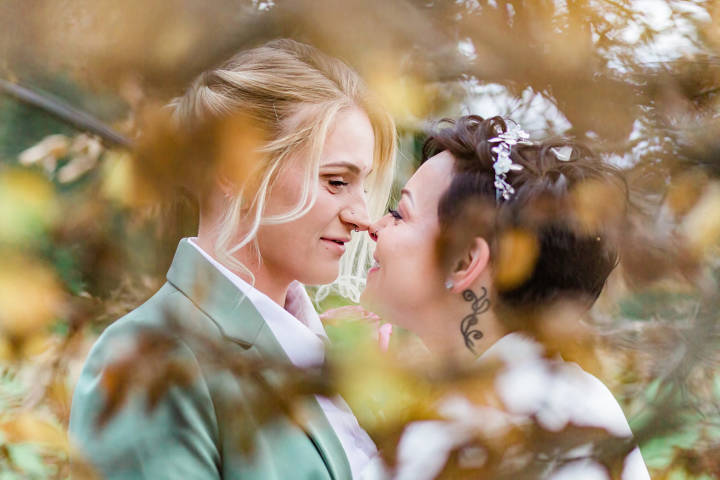 Intimate photo of brides through autumn foliage at Leatherhead Registry Office