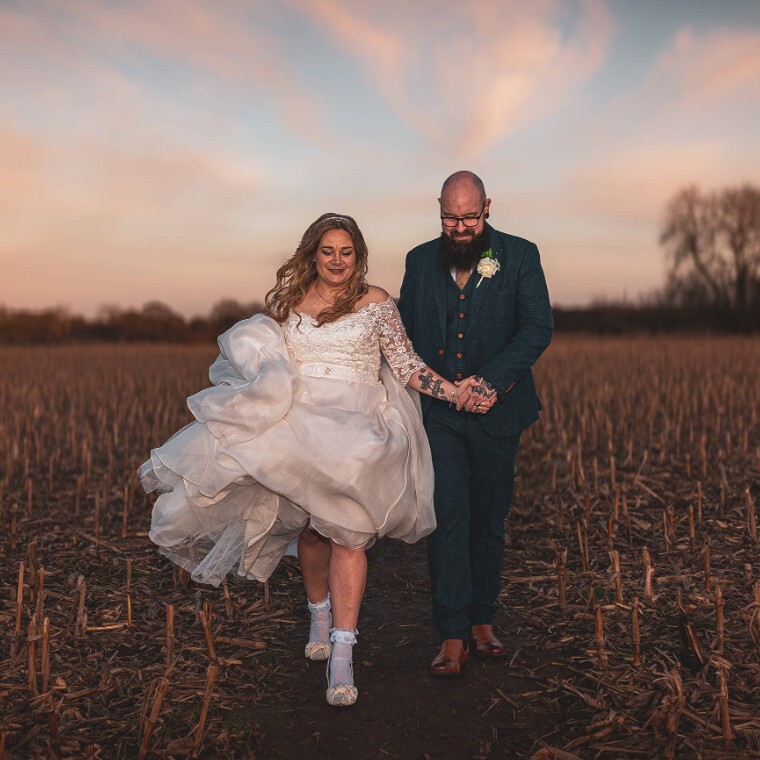 A couple walking across a field in golden our
