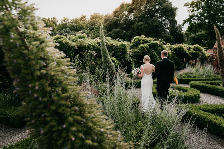 Bride and groom walking through the Fulham Palace Gardens on wedding day