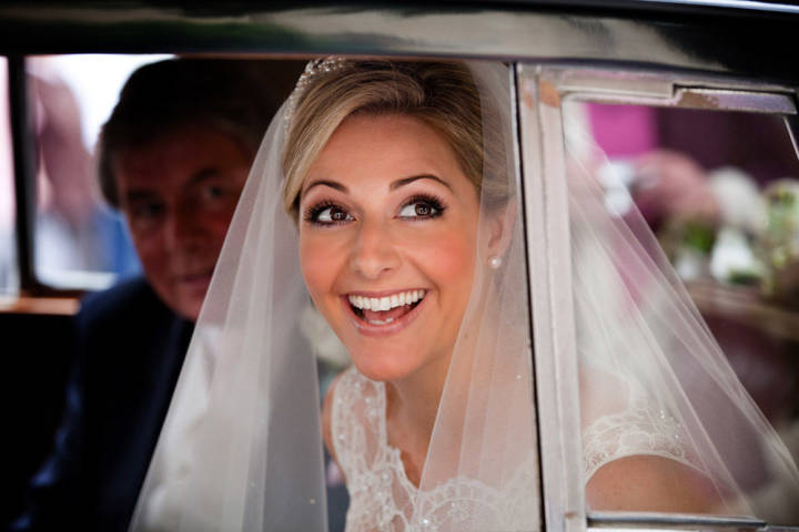 Beautiful bride looking out of car laughing