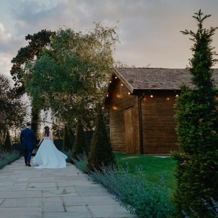 A bride and groom walking through the garden at an exclusive Warwickshire wedding venue