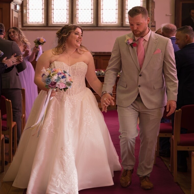 Wedding couple walking down the aisle hand in hand after ceremony, bride laughing, Somerset church