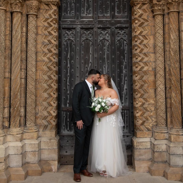 Bride and groom in front of ornate church doorway, romantic wedding portrait by Massey Photography, Lincoln, Lincolnshire