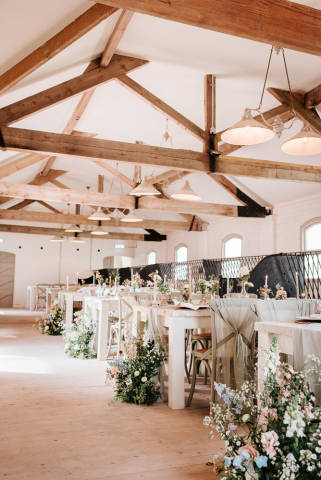 Renovated barn dining room with tables decorated with bright pastel flowers