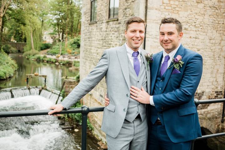 Two grooms standing on the bridge at Egypt Mill on their wedding day