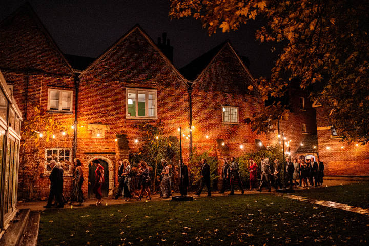 Wedding guests walk into Fulham Palace at night