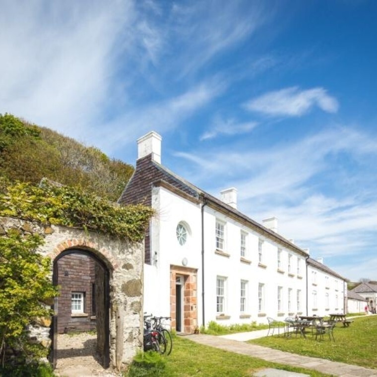 Front of Manor House Rathlin with blue skies and greenery.