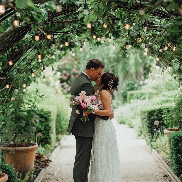 Couple under Apple Arch at Outdoor Garden Wedding in Pippley Walled Garden