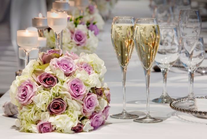 Floral bouquet and champagne on table with candles
