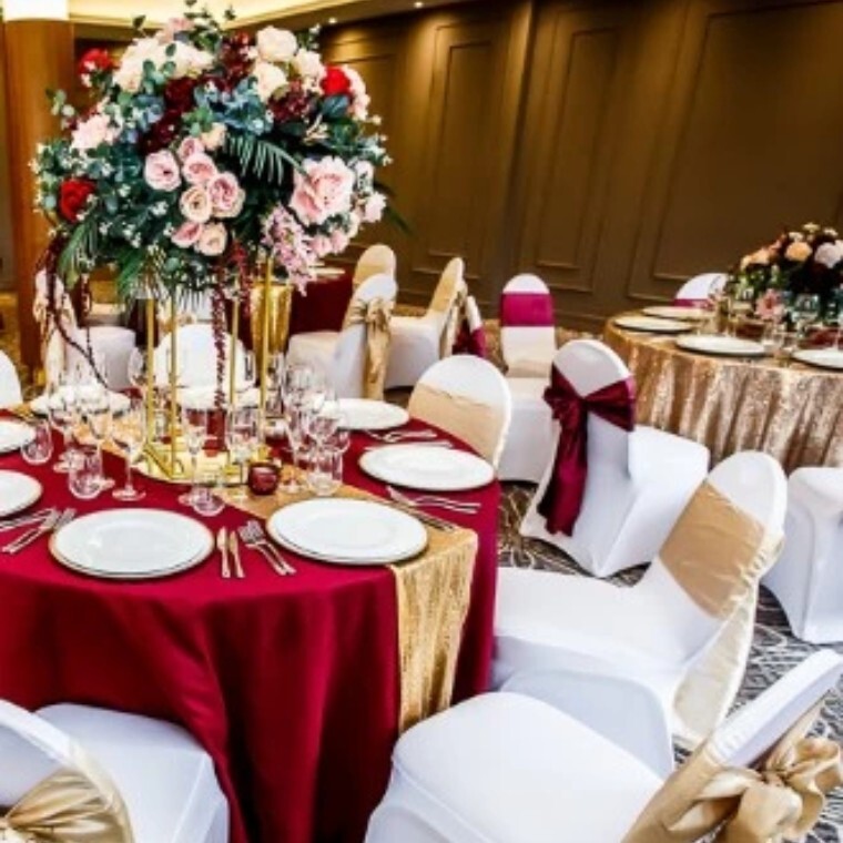Wedding table with red cover, gold decorations and beautiful flower centre piece.