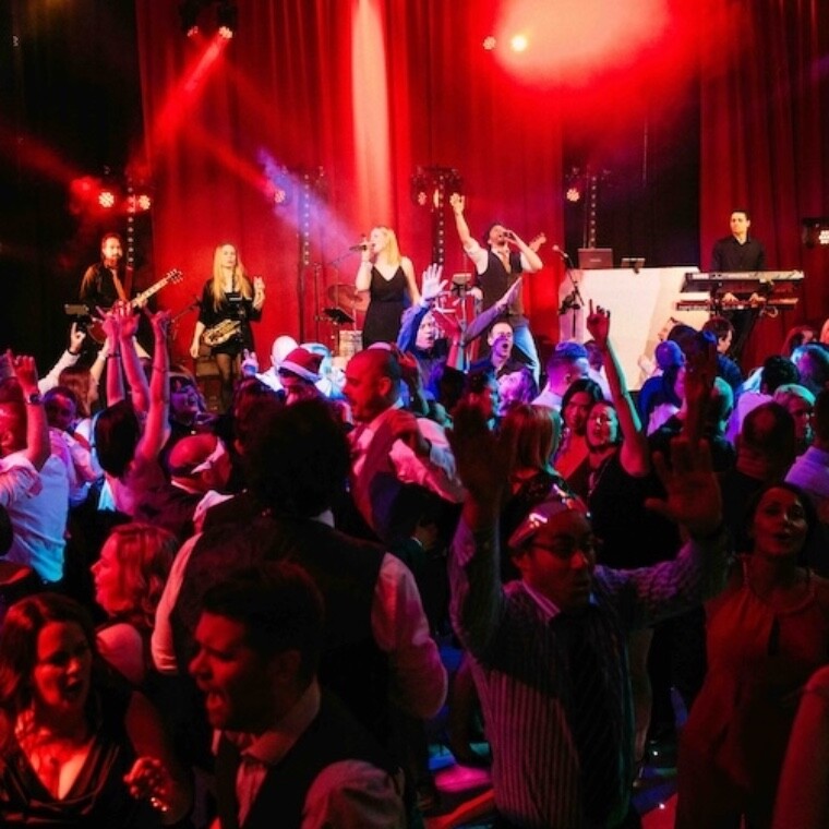 Under the Covers Wedding Band entertaining a packed dance floor with people putting their hands in the air