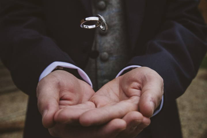 Wedding rings drop into groomsman's hand, photographed frozen in the air
