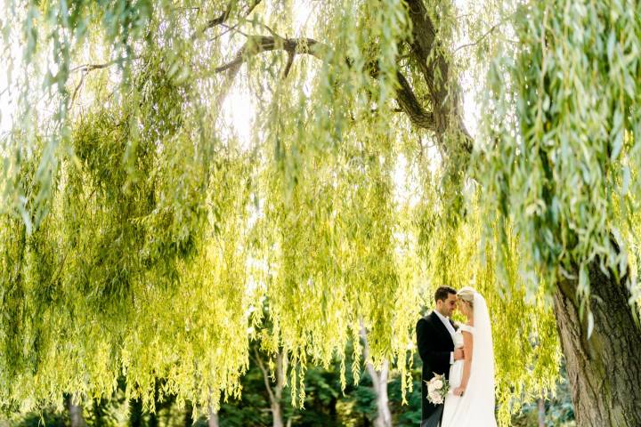 Couple stood under a willow tree at Eastington Park in Gloucestershire