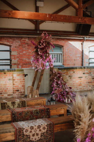 Ceremony set up with benches and a wooden triangle podium at the front covered in bright pink flowers