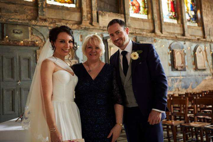 Wedding couple standing with Celebrant in a London Chapel