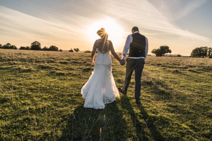 Couple holding hands walking into the sunset.