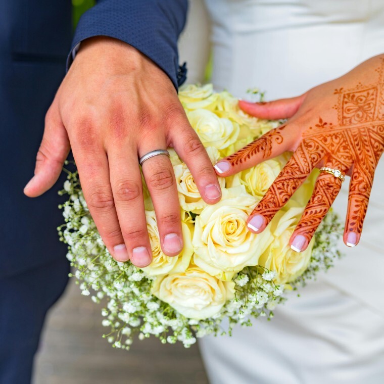 Bride and grooms hand on bouquet, the brides hand has henna on it