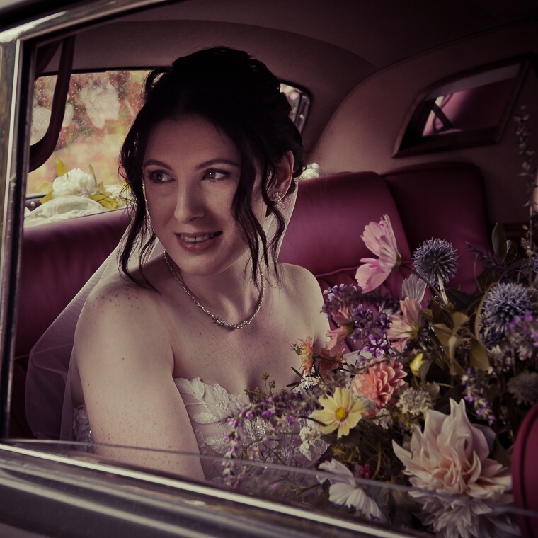 Bride arrives at wedding ceremony and looks through open window of the car