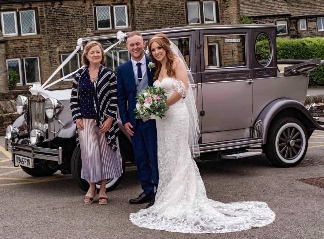 Bride and groom stood in front of a vintage car