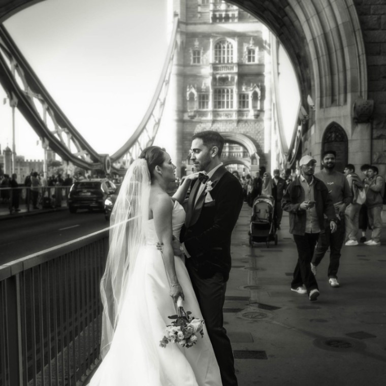 A bride and groom stand together on Tower Bridge during their black tie London wedding day.