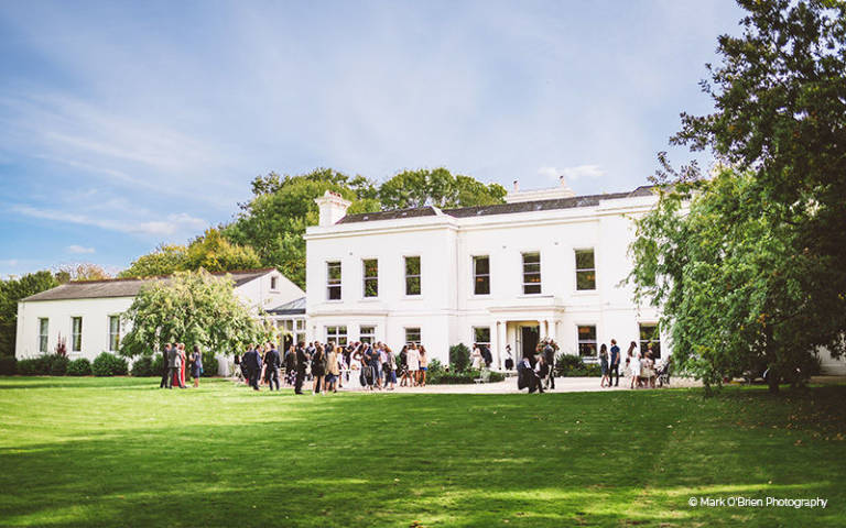 Wedding guests enjoy the sunshine in the gardens at Morden Hall