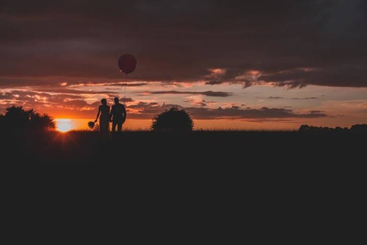 Couple holding hands walking into the sunset.