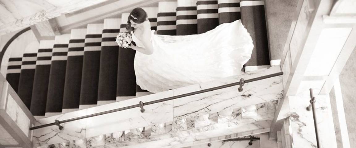 Black and white photo of a bride descending the stairs
