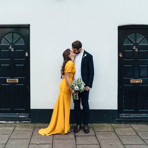 A woman in a yellow dress kissing a man in a suit