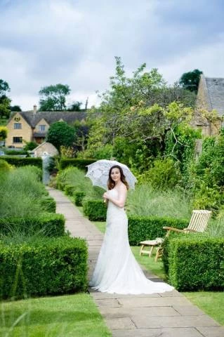 Bride Holding Parasole in Gardens of Cotswold House Hotel and Spa, Venues in Chipping Campden, Gloucestershire