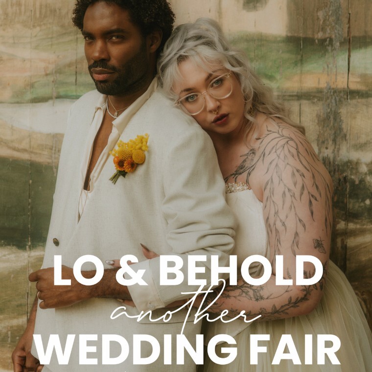 A bride and groom embrace infront of a painted backdrop found on the Singing Theatre at Larmer Tree. Lo & Behold Another Wedding Fair.