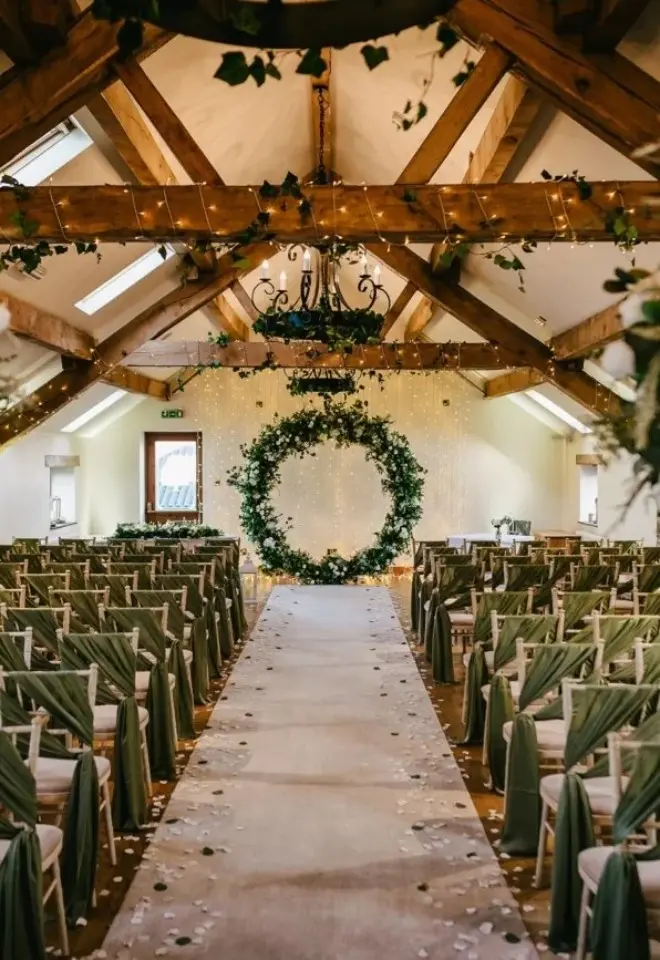 Ceremony room in Beautiful Barn with green seat covers and wreath.