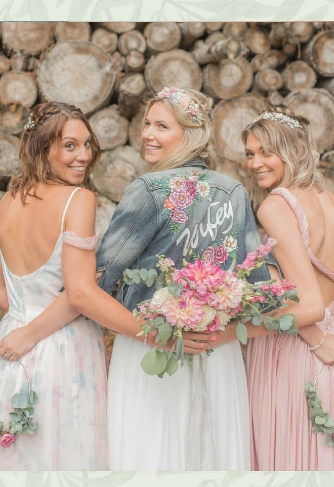 Wifey denim jacket bride is wearing next to bridesmaids holding their flowers