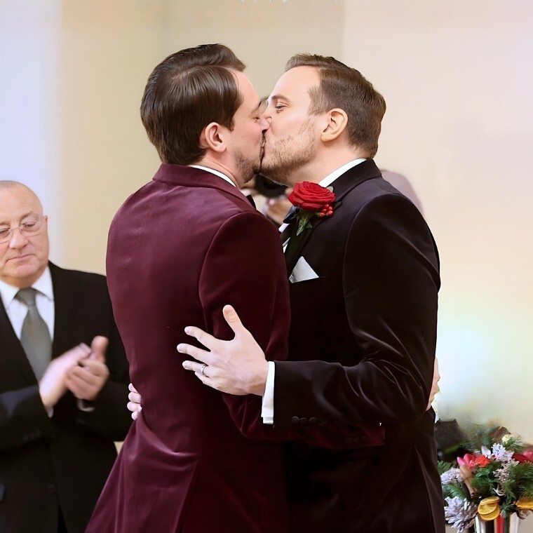 Two grooms kissing during their wedding ceremony at farnham castle